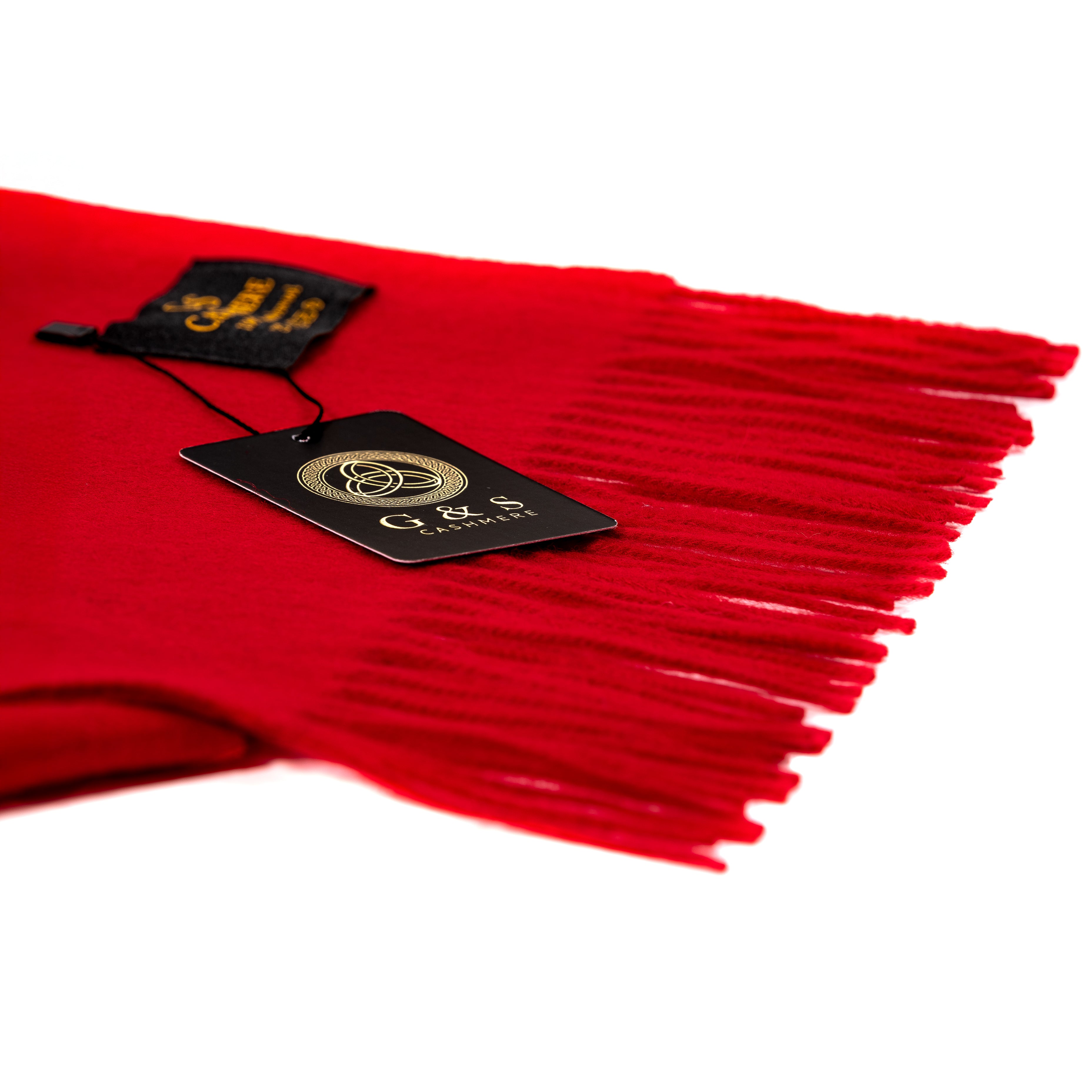 Close-up of Ruby Echo lambswool scarf highlighting vibrant red fabric, soft finish, fine fringe detailing, and branded tag for a premium luxury feel