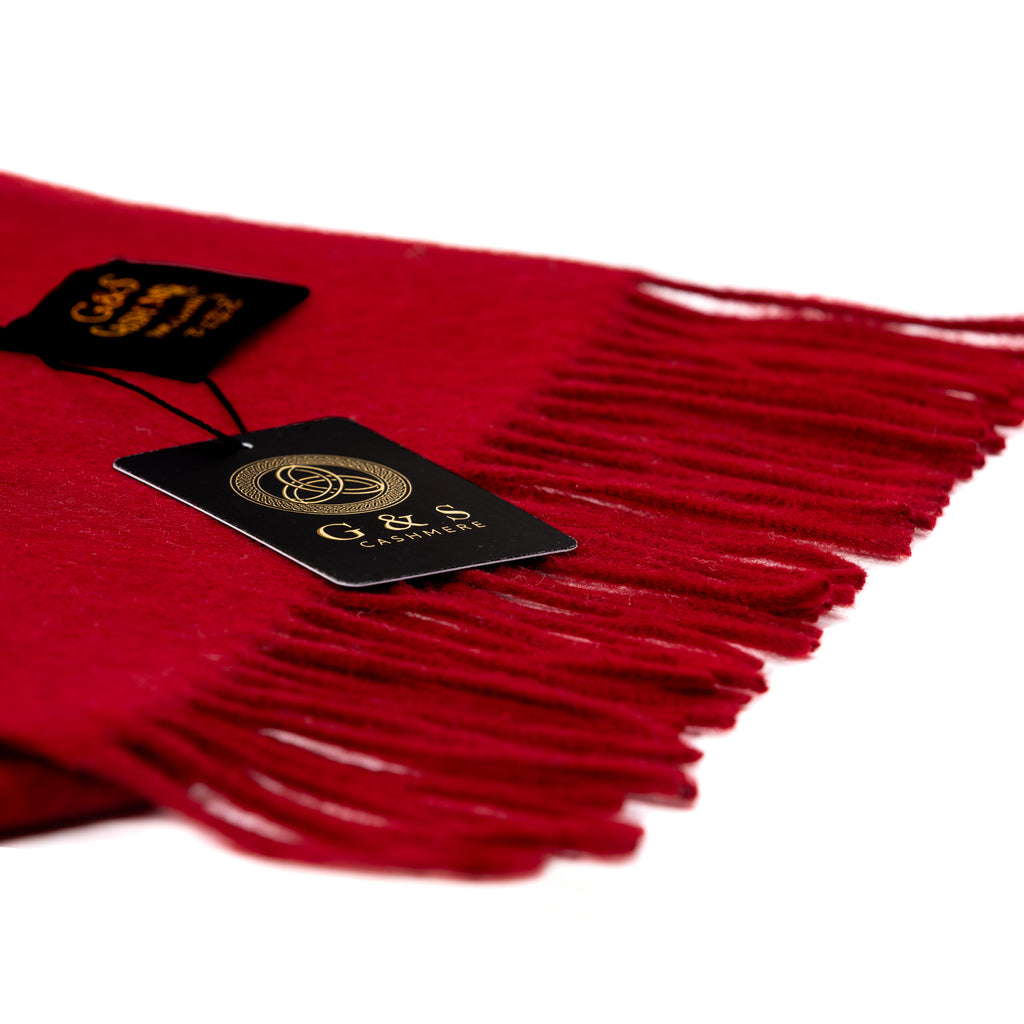 Close-up of Cardinal Vale lambswool scarf highlighting rich red fabric, soft brushed texture, delicate fringe detailing, and premium branded tag