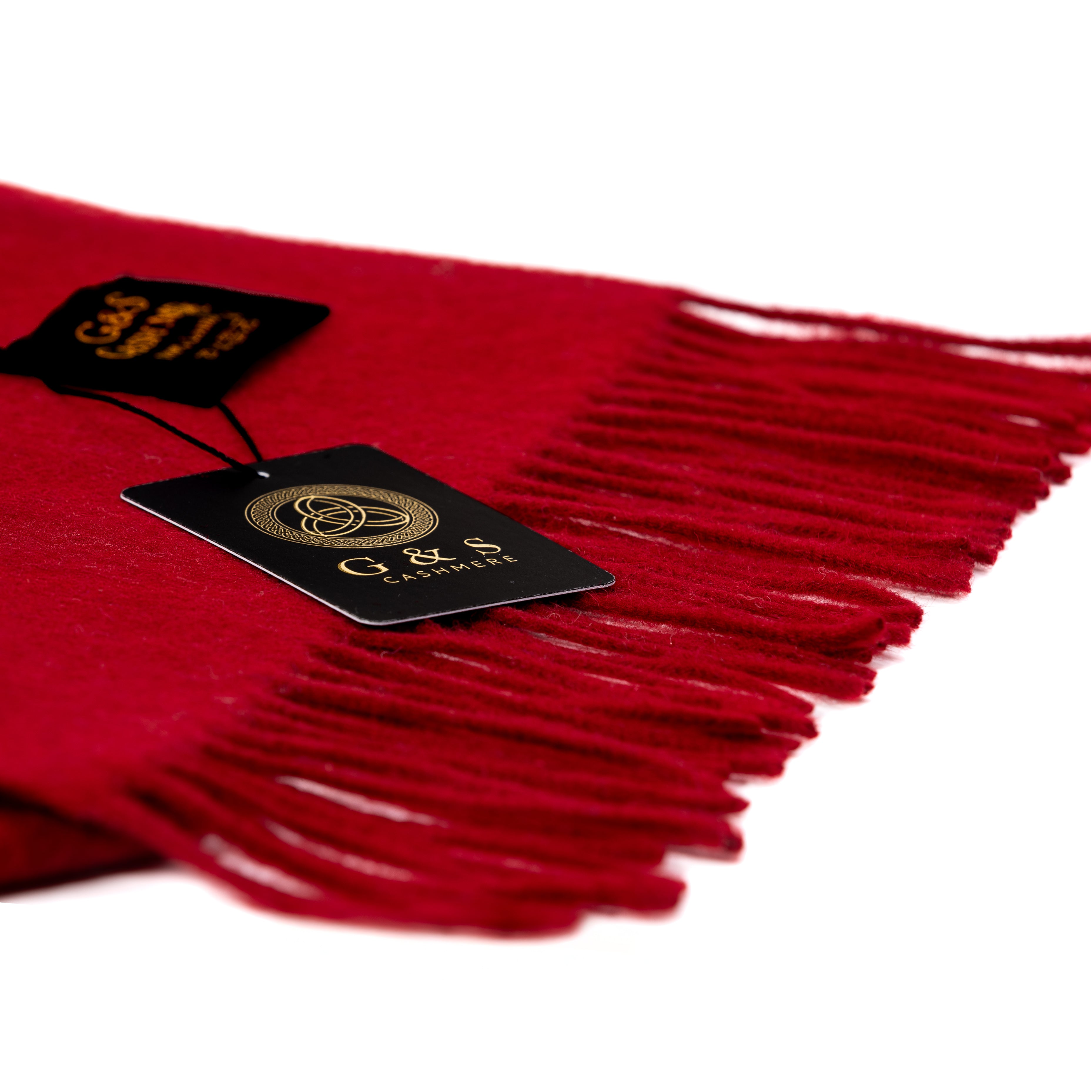 Close-up of Cardinal Vale lambswool scarf highlighting rich red fabric, soft brushed texture, delicate fringe detailing, and premium branded tag